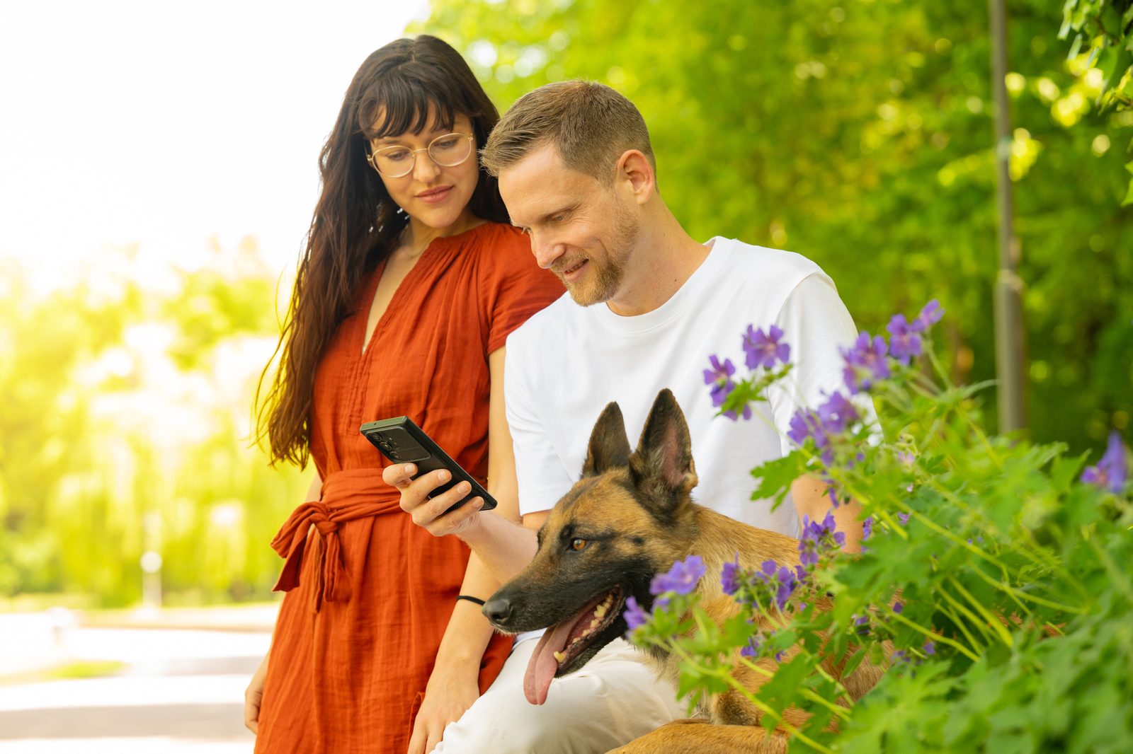 Ronja und Clemens schauen gemeinsam aufs Handy, Mali sitzt daneben